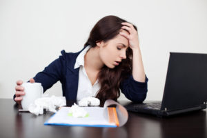 Sick woman at work with headache